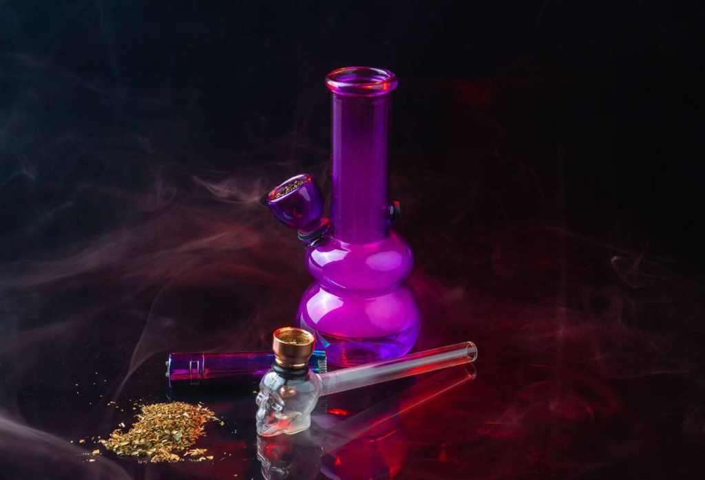 a purple glass bong with a skull and a glass pipe